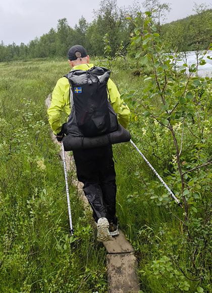 Ingo läuft auf einem Trail aus Holzplanken durch die Wiese